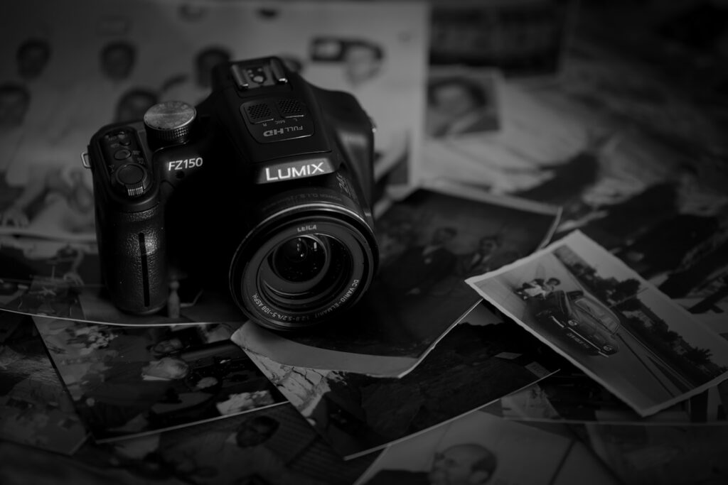 Digital camera rests on scattered old black and white photographs.